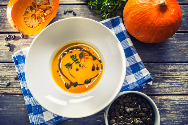 Pumpkin cream soup with seeds and parsley on kitchen table - Foto, Imagen