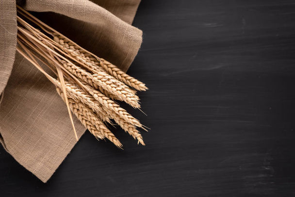 spikelet of wheat lying on the table in a dark color. Ripe and Golden Wheat - Fotó, kép