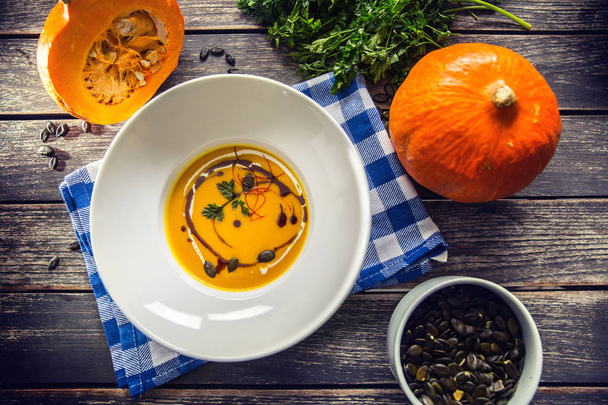 Pumpkin cream soup with seeds and parsley on kitchen table - Top of view - Foto, Imagen