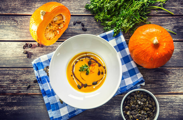 Pumpkin cream soup with seeds and parsley on kitchen table - Top of view - Foto, Imagen