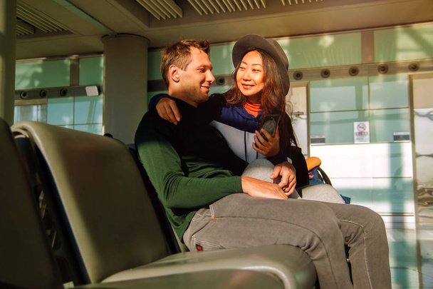 Ευτυχισμένο ζευγάρι χρησιμοποιώντας το κινητό τηλέφωνο στο αεροδρόμιο. - Φωτογραφία, εικόνα