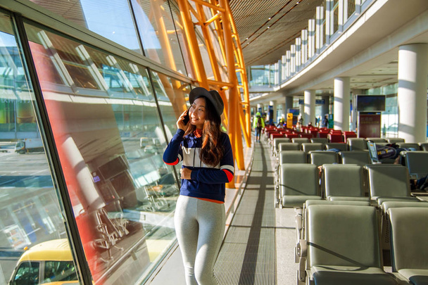 Азіатські жінки, використовуючи стільниковий телефон в аеропорту, дивлячись вікна. - Фото, зображення