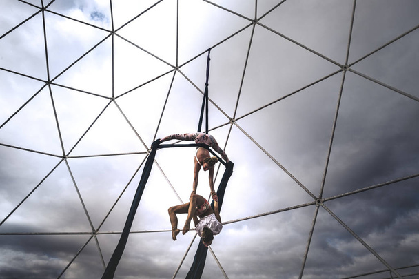 Paar meisjes in omgekeerde positie doen acrobatische fitness tentoonstelling show activiteit buiten met cirkel in evenwichtige posities voor een gezonde alternatieve sport levensstijl - Foto, afbeelding