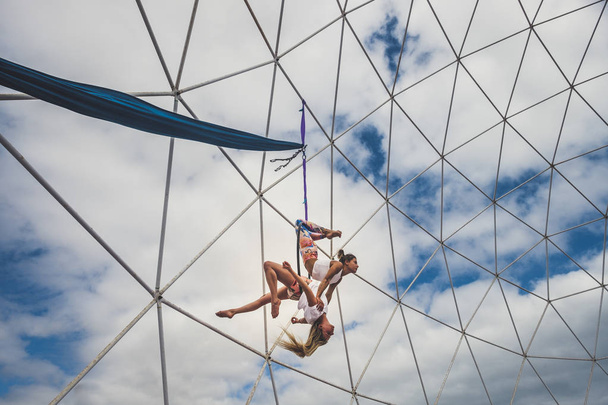 Pari tyttöä käänteisessä asennossa tekemässä akrobaattinen kunto näyttely näyttää toimintaa ulkona ympyrä tasapainossa asemissa terveen vaihtoehtoisen urheilun elämäntapa - Valokuva, kuva