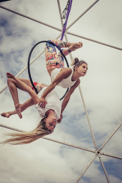 Couple of girls in reverse position doing acrobatic fitness exhibition show activity outdoor with circle in balanced positions for healthy alternative sport lifestyle - Photo, Image