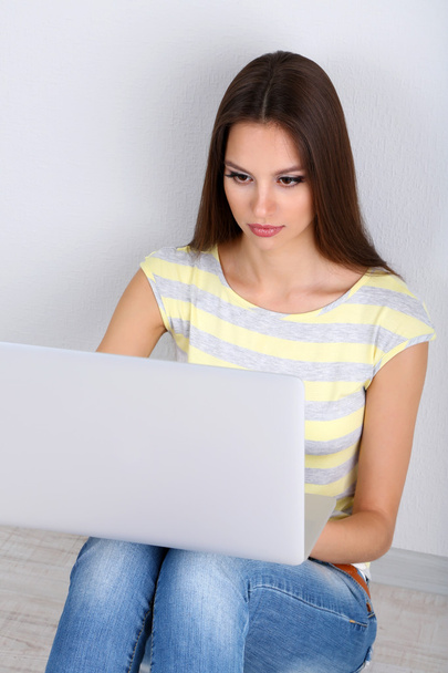 mooie jonge vrouw zitten met laptop in de kamer - Foto, afbeelding