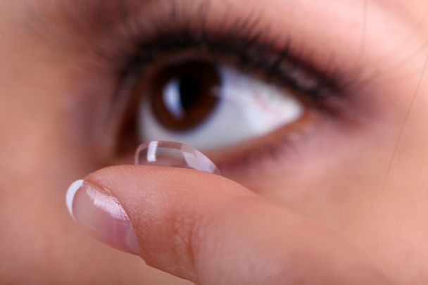 Young woman putting contact lens in her eye close up - Photo, image
