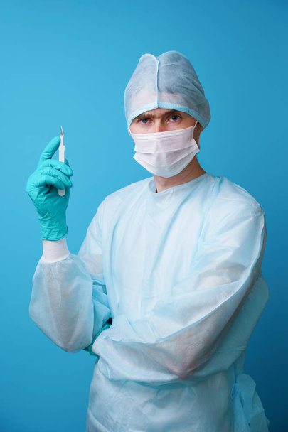 Chirurg in steriel blauw uniform, medische handschoenen en masker - Foto, afbeelding