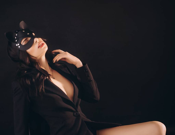 Beautiful young woman posing in black jacket and cat mask - Foto, Imagem