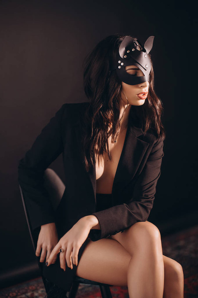 Kaunis nuori nainen poseeraa musta takki ja kissa naamio
 - Valokuva, kuva