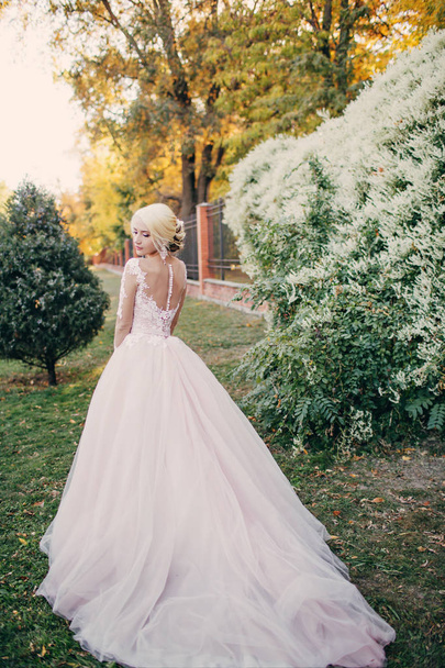 Красивая молодая невеста в белом свадебном платье позирует в парке
 - Фото, изображение