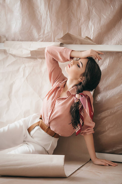 Beautiful young woman posing in pink blouse and white pants - Фото, изображение