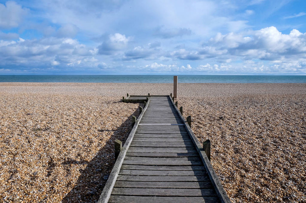 long sentier droit en bois sur la plage de galets menant à la mer
 - Photo, image