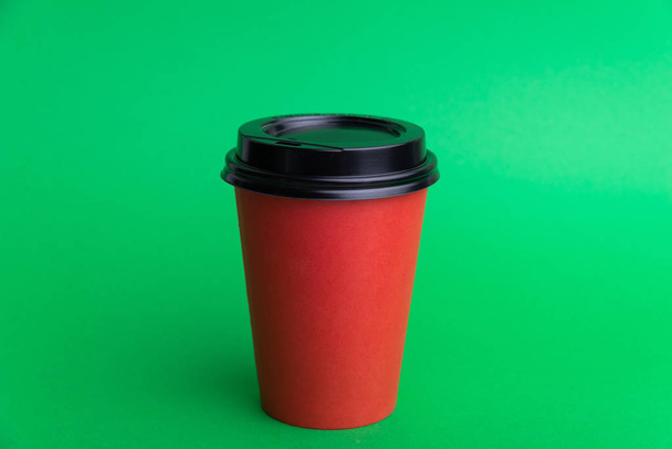 Фото червоної чашки з чорною шапочкою на зеленому тлі
  - Фото, зображення