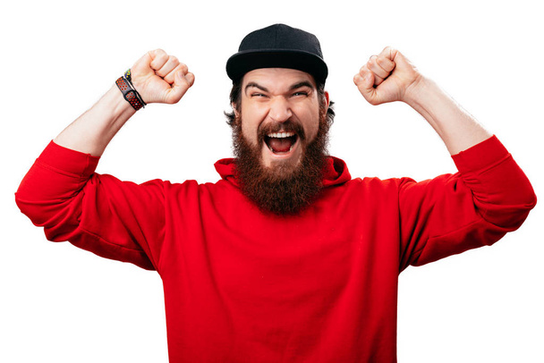 Excited bearded guy, screaming and celebrating with rised arms over white background  - Photo, Image