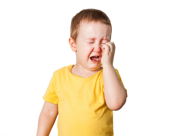 Плачущий мальчик в желтой футболке закрывает лицо руками и криками, студия изолирована на белом фоне
 - Фото, изображение
