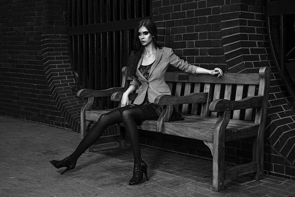 Young fashion model outdoor shoot posing wearing short black dress - Foto, imagen