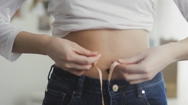 Mujer joven midiendo su cintura con cinta métrica
 - Imágenes, Vídeo