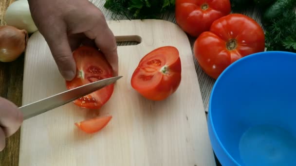 Cuisine végétarienne maison saine. Des mains humaines coupent des tomates rouges juteuses pour cuisiner une salade de légumes sur une planche à découper en bois
. - Séquence, vidéo