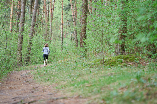Athlétique jeune femme en baskets roses courir dans la forêt de printemps
 - Photo, image
