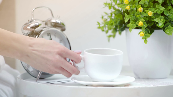 vue recadrée de la jeune femme prenant tasse avec café près du réveil et plante
  - Séquence, vidéo