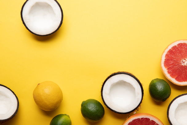 top view of citrus fruits and coconuts on yellow background with copy space - Foto, imagen