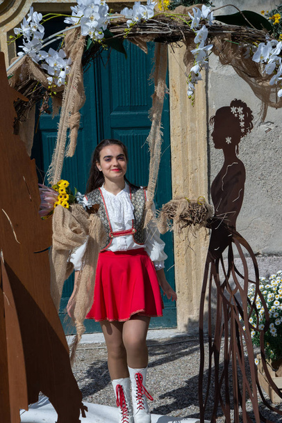 Girl wearing a majorette uniform, outdoors, portrayed among a metal figure marriage concept. Country of Castellaro Lagusello, Monzambano, Mantua, Italy, Europe. Show annual flower market. - Photo, Image