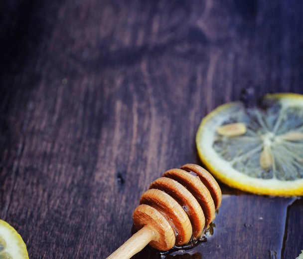 Hunajaa ja sitruunaa. Hunajatikku ja viipaleita viipaloitu sitruuna puinen pöytä. Tee kupissa ja makea limettihunaja purkissa
 - Valokuva, kuva