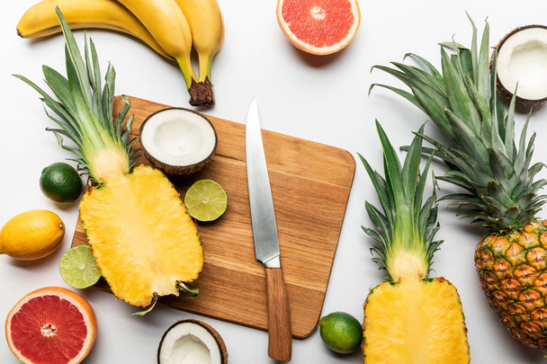 beyaz arka plan üzerinde bıçak yakın ahşap doğrama tahtası üzerinde kesim ve bütün tropikal meyve üst görünümü - Fotoğraf, Görsel
