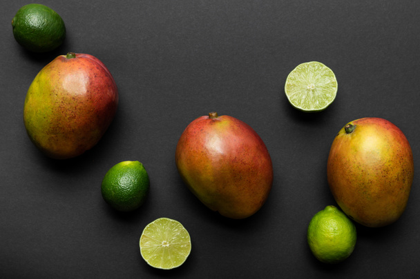 top view of ripe limes and mango on black background - Foto, imagen