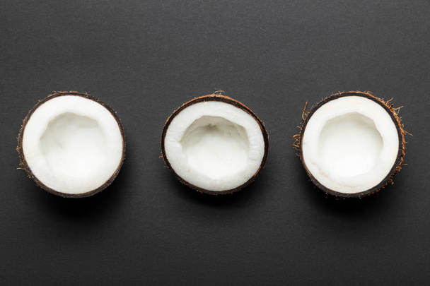 top view of coconut halves on black background - Foto, Imagem
