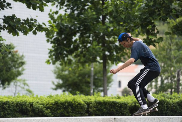 BILBAO, ESPANHA - JULHO 14, 2016: Um adolescente pratica com seu skate em um banco de pedra, em uma das ruas da cidade
. - Foto, Imagem