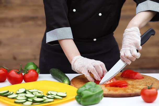 El cocinero corta verduras frescas de granja para cenar en la mesa
 - Foto, imagen