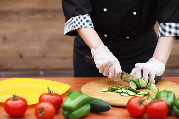 Кухар розрізає свіжі фермерські овочі на обід на столі
 - Фото, зображення