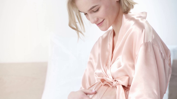 gelukkige zwangere jonge vrouw aanraken van buik en glimlachend thuis  - Video
