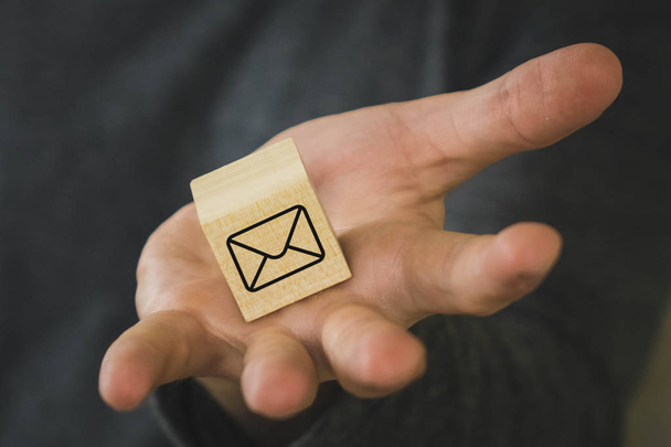 ξύλινο κύβο στο χέρι του ανθρώπου με το σύμβολο του μηνύματος, γράμμα - Φωτογραφία, εικόνα