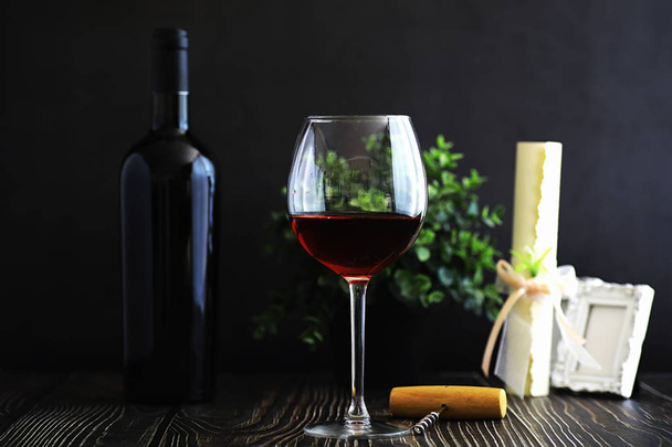 A glass of red dry wine on a table. Dark bottle and glass of wine. - Photo, Image