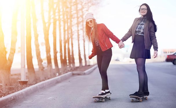 Uma jovem hipster está montando um skate. Meninas namoradas f
 - Foto, Imagem