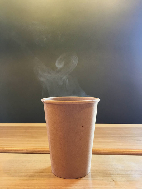 Jednorazowa filiżanka kawy, aby przejść na drewnianym stole w kawiarni. - Zdjęcie, obraz