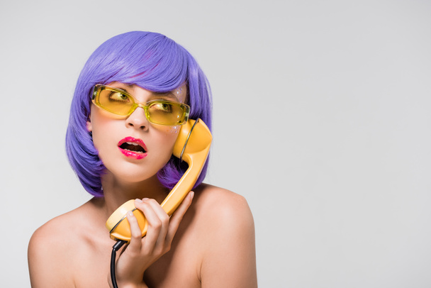 bored woman in purple wig holding retro telephone, isolated on grey - Zdjęcie, obraz