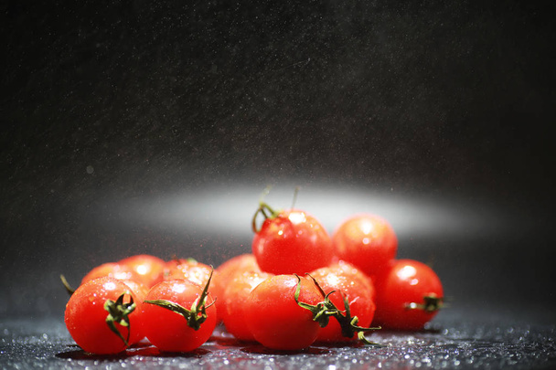 Вишневі помідори на чорному тлі в розпилювачі
 - Фото, зображення