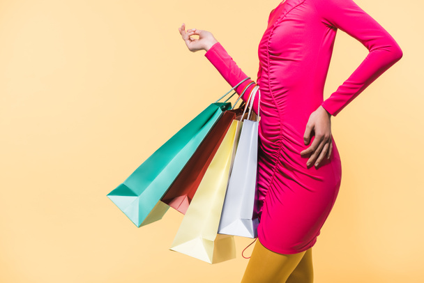 oříznutý pohled stylové ženy s nákupními sáčky, izolované na žluté - Fotografie, Obrázek
