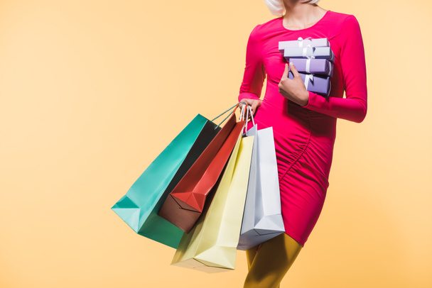 vista cortada de mulher com presentes e sacos de compras, isolado em amarelo
 - Foto, Imagem