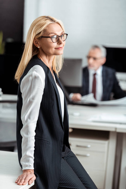 selective focus of happy businesswoman in glasses standing near businessman  - Фото, изображение