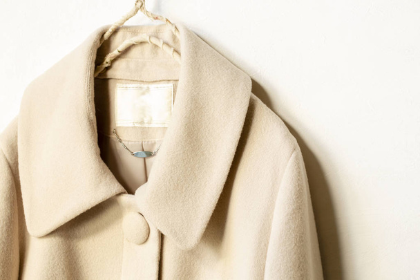 beige wool coat hanging on clothes hanger on white background - Foto, imagen
