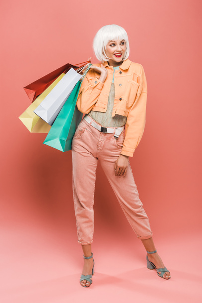 Atrakcyjna dziewczyna uśmiechnięta w białej peruce z torby na zakupy na różowy - Zdjęcie, obraz
