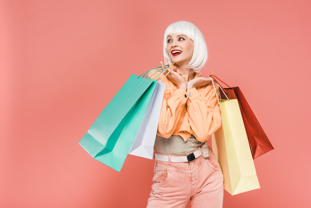 trendy woman in white wig with shopping bags, isolated on pink - Фото, изображение