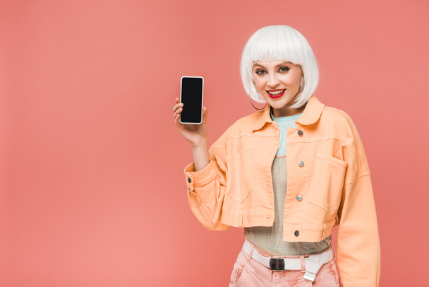 красивая женщина показывает смартфон с пустым экраном, изолированный на розовый
 - Фото, изображение