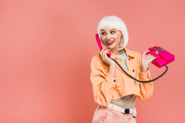 beautiful young woman in white wig talking on retro telephone, isolated on pink  - Foto, Imagen