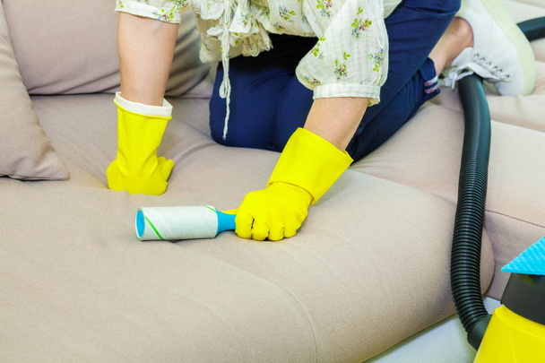 Женщина чистит диван с липким роликом
 - Фото, изображение